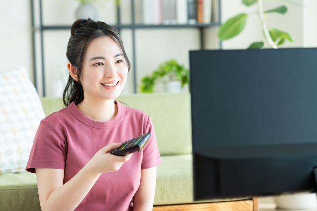 テレビのリモコンで年齢区分(映倫P-12)画面をチェックしている女性